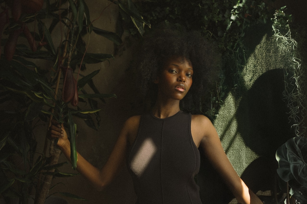 A NITISI piece worn among living plants, lit by dappled light